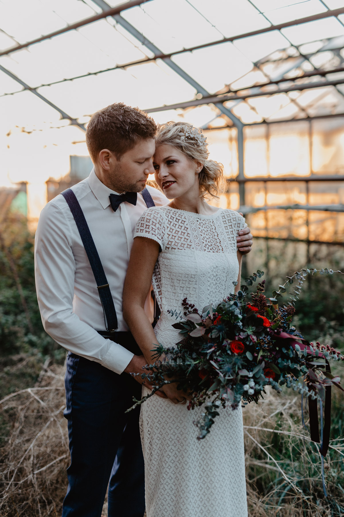 Herbsthochzeit – Brautpaar mit herbstlichem Brautstrauss in einem Gewächshaus