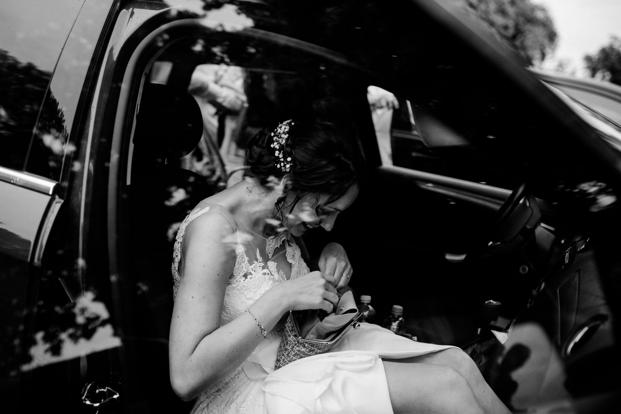 Braut schaut in ihre Schminktasche während sie im Brautauto sitzt